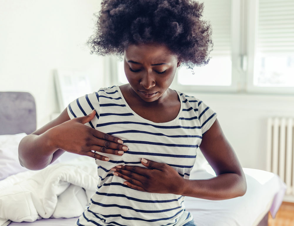 Woman examining her breast on bed