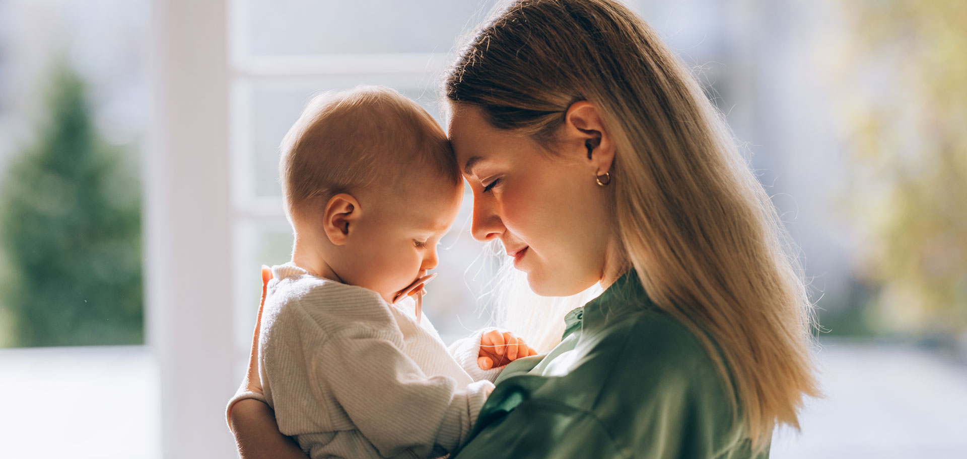 Mother gently touching forehead with baby indoors