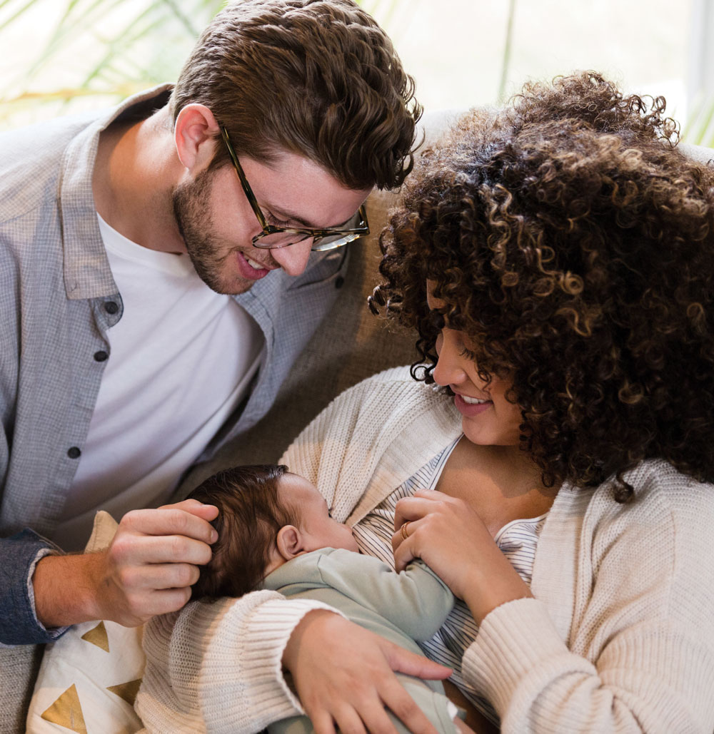 Father touching baby's head as mother breastfeeds